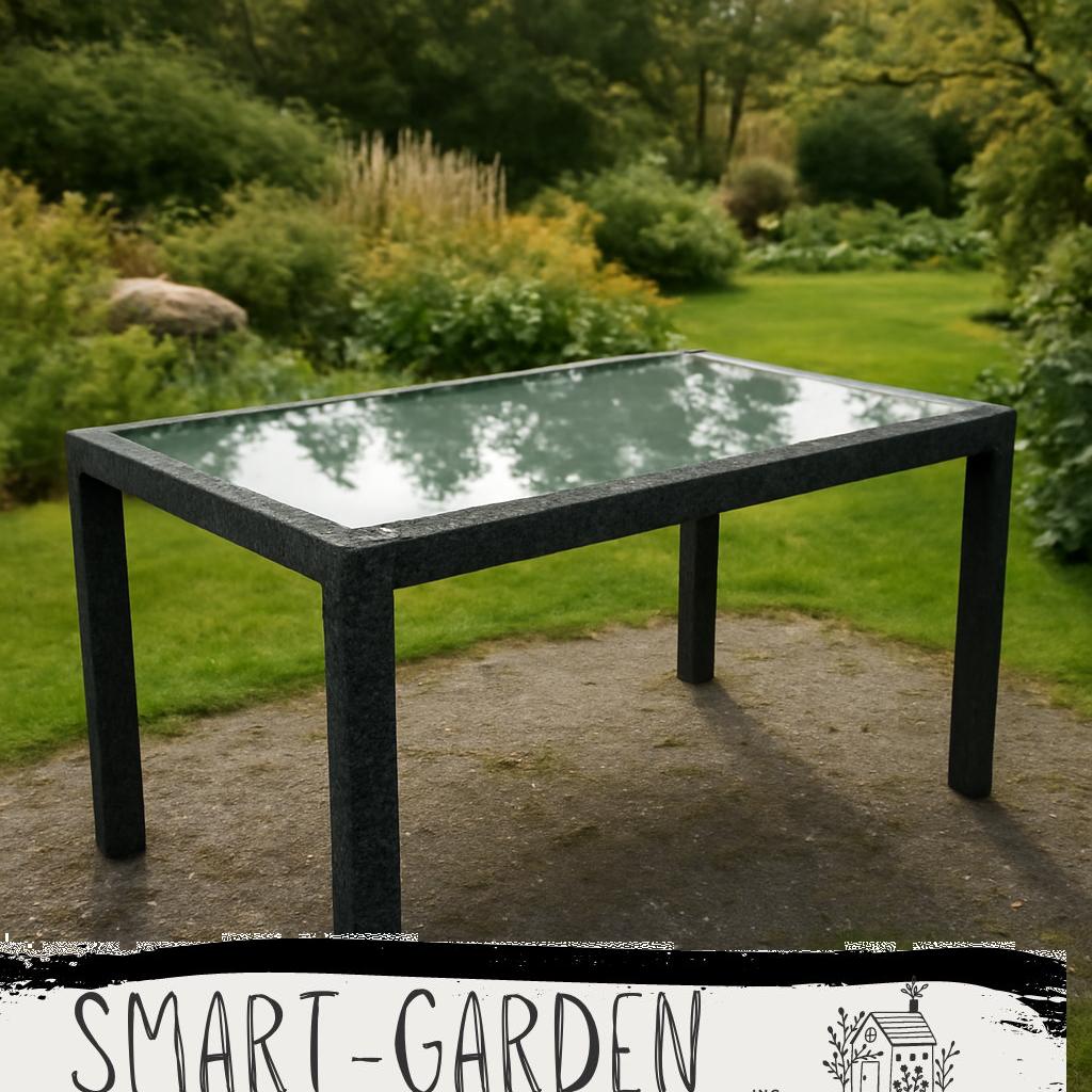 ALT-Text: Moderner Gartentisch mit Glasplatte auf einer sonnigen Terrasse im Garten, umgeben von grünen Pflanzen und gemütlichen Stühlen